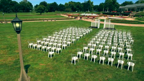 Aerial-circling-over-wedding-set-up-with-white-chairs-and-elegant-arch-at-Garfield-Park-conservatory-of-Indianapolis,-Indiana