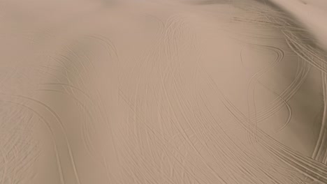Drone-Footage-of-Desert-Sand-with-ATV-Tracks,-Dune-Buggies-Driving-on-Peaks-in-Daytime