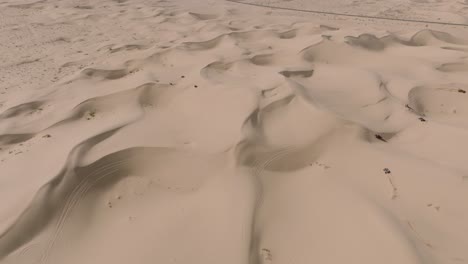Aerial-Drone-Footage-of-Sand-Dune-Off-Roaders-on-ATV's,-Driving-Over-Sandy-Peaks-in-Sunny-California-Desert