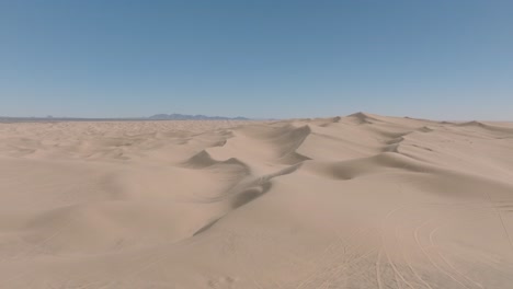 Drohne-Fliegt-über-Weite-Sanddünenlandschaften-In-Südkalifornien,-Blauer-Himmel-Voraus-Und-Weicher-Sand-Unten