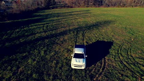 Aerial-drone-tracking-scene-of-white-Silverado-pickup-truck-driving-on-green-grassy-lawn-of-rural-area-in-Indianapolis