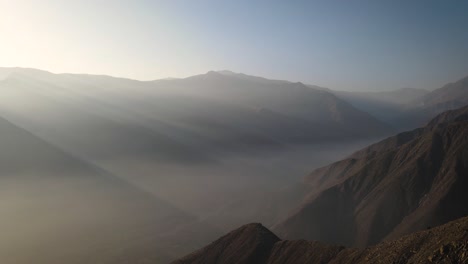 Tiro-De-Drone-Retroiluminado-De-Montañas-Nubladas-Que-Muestran-Enormes-Haces-De-Luz-En-Perú