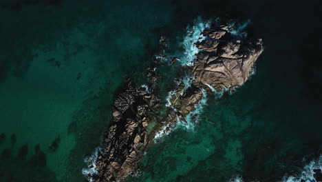Rotierende-Luftdrohnenaufnahmen,-Die-Die-Wellen-Einfangen,-Die-über-Die-Felsen-Der-Insel-La-Digue-Auf-Den-Seychellen,-Afrika,-Schlagen