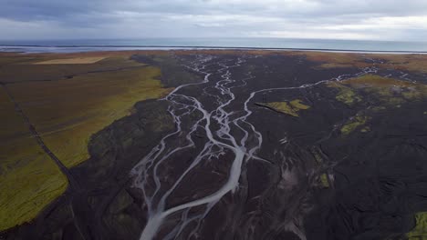 Icelandic-weaving-glacial-river---Dramatic-Bird's-eye-view-flying-towards-the-ocean-on-a-cloudy-day