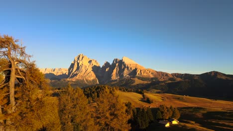 Mountains,-forest-and-grass-fields-with-wooden-cabins-filmed-at-Alpe-di-Siusi-in-Alps,-Italian-Dolomites-filmed-in-vibrant-colors-at-sunset