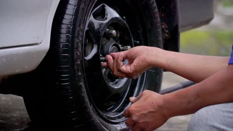 Close-up-shot-of-man-hand-fit-the-nut-on-the-car-tyre-after-replace-the-tyre