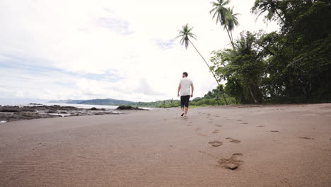 caucasian-male-tourist-traveller-walking-alone-in-tropical-white-sand-beach-paradise-in-Costa-Rica-Central-America-travel-holiday-destination