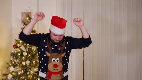 Happy-young-man-throws-a-nut-and-catches-it-in-his-mouth-and-starts-dancing-in-front-of-a-Christmas-tree