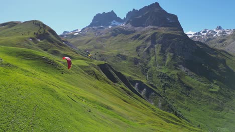 Paragliders-fly-above-green-mountain-valley-in-French-Alps---Aerial