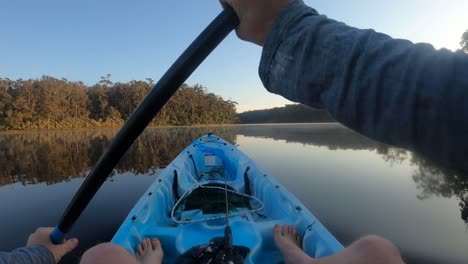 A-point-of-view-shot-of-a-man-paddling-a-kayak-on-a-misty-lake-in-the-early-morning-in-Australia