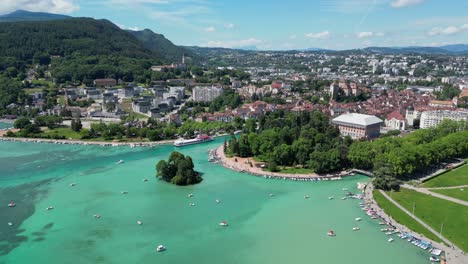 Cityscape-and-Boats-at-Turquoise-Light-Blue-Lake-Annecy,-France---Aerial