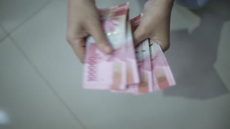 woman-hand-showing-rupiah-Indonesian-money
