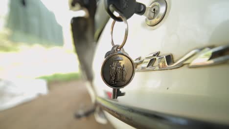 Car-keys-in-a-lock,-keychain-with-religious-symbols