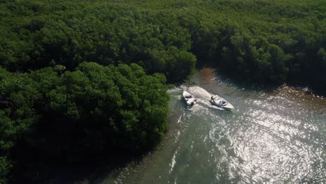 Near-boating-accident-between-two-power-boats-passing-each-other-while-moving-through-mangrove-forest-in-water-canals-of-Riviera-Maya,-Mexico-creating-a-wake-in-the-ocean-water