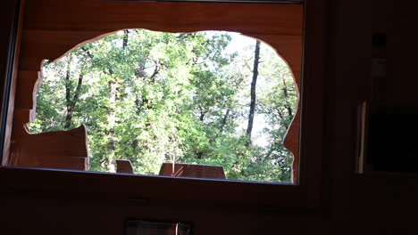 Silhouette-Eines-Skulptierten-Bären-In-Einer-Holzhütte,-Blick-Auf-Die-Bäume-Eines-Waldes-Im-Hintergrund