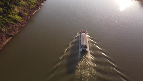 Eine-Tracking-Luftaufnahme-Eines-Touristenboots-Auf-Dem-Iguazu-Fluss-Bei-Sonnenuntergang