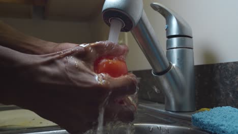 Schwarzer-Mann-öffnet-Wasserhahn-Und-Spült-Rote-Tomate-In-Der-Spüle---Mittlere-Aufnahme