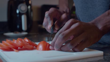 Hombre-Negro-Cortando-Tomates-Rojos-Frescos-En-Una-Tabla-De-Cortar-Blanca-De-Plástico-En-La-Cocina