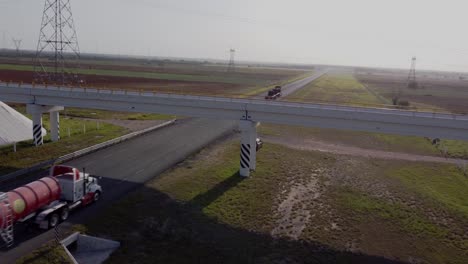 Remolques-En-Carretera-Asfaltada-En-Reynosa,-Tamaulipas,-México-Con-Un-Puente-En-Un-Día-Soleado,-Tiro-De-Drones-4k