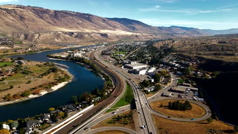 Drone-pan-right-aerial-shot-of-Bridges,Highway-1-and-Yellowhead-Highway-in-the-City-of-Kamloops-BC-Canada,train,trucks,-the-Thompson-River-on-a-Cloudy-Day-in-a-desert-environment