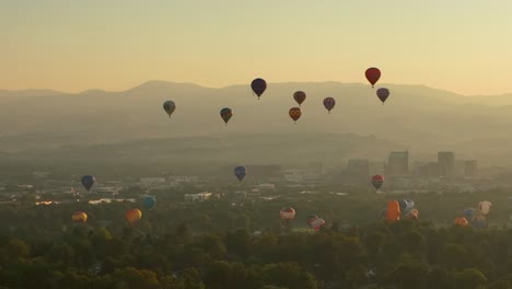 Silhouette-view-of-numerous-hot-air-balloons-taking-off-from-a-valley