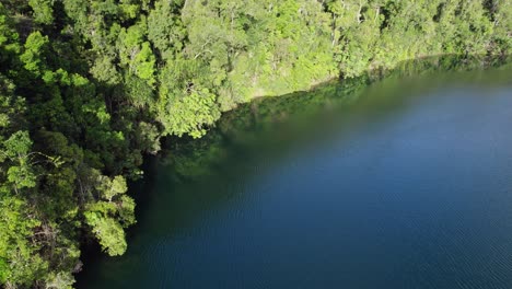Flight-Over-Calm-Waters-Of-Lake-Eacham-In-Atherton-Tableland,-Queensland,-Australia---drone-shot