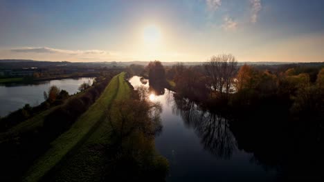 Aerial-drone-view-over-the-river-and-autumn-trees-from-the-forest-during-sunset