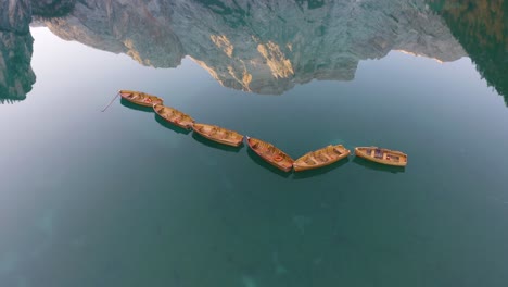 Fixed-Aerial-View-of-Wooden-Row-Boats-on-Beautiful-Lake,-Mountain-Reflection
