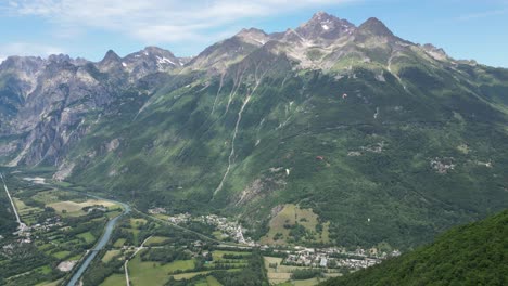 Paragliders-floating-above-Eau-d'Olle-valley-in-Alpe-d'-Huez,-French-Alps---Pan-Right