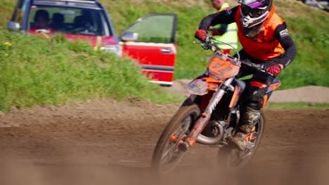 Following-shot-of-a-motor-cross-rider-diving-on-a-bumpy-off-road-track-on-a-sunny-day