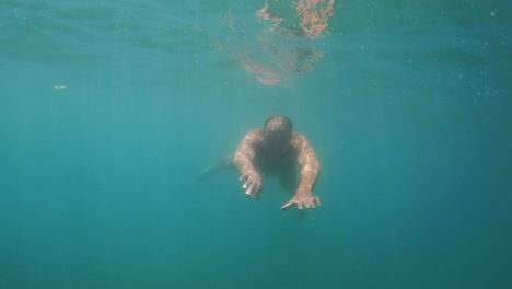 Unterwasser-Zeitlupenszene-Eines-Erwachsenen-Mannes-In-Apnoe,-Der-Lächelnd-In-Richtung-Kamera-Schwimmt