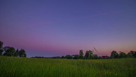 Dramatic-evening-sunset-to-sunrise-time-lapse-of-a-green-landscape,-clouds-passing-overhead,-little-house-in-corner-in-the-middle-of-nowhere