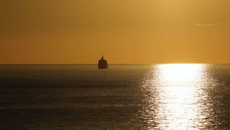 Ocean-orange-sunset-landscape,-cargo-ships-sail-in-evening-light