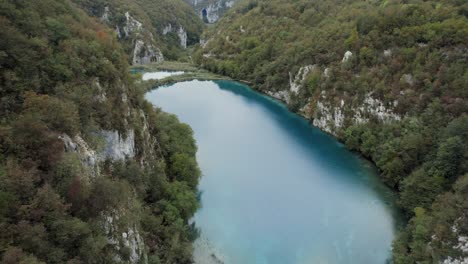 Flyover-shot-over-river-in-wooded-rocky-canyon-in-Plitvice,-Croatia