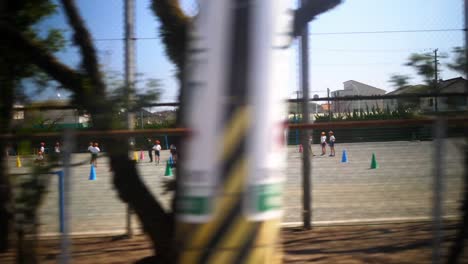 Japanese-kids-making-exercises-at-schoolyards-at-sunny-day,-view-from-car