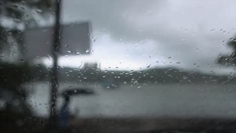 An-abstract-shot-looking-through-a-window-covered-in-water-droplets-along-the-Mahadayi-River-on-a-dark-gloomy-rainy-day,-Panjim,-India