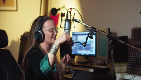 Woman-with-headphones-and-a-microphone,-singing-and-very-expressively-experiencing-her-part