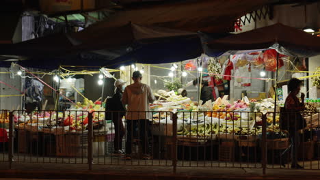 Static-shot-of-locals-shopping-in-a-food-market-at-night-in-an-Asian-town