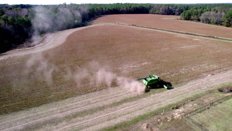 Drone-footage-of-soy-bean-harvesting-on-a-farm-field-with-a-harvester-or-tractor,-rotating-aerial-shot