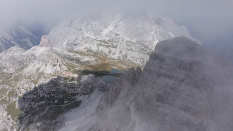 Mountain-pass-with-a-lake-emerging-from-the-clouds,-Rifugio-Locatelli-in-Tre-Cime-area-of-Dolomites