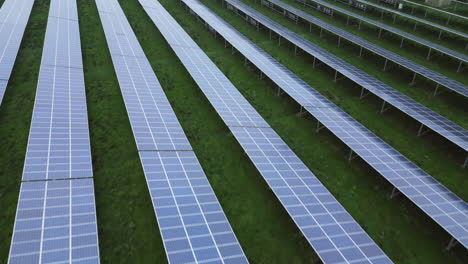 Solar-panels-in-solar-park,-endless-patterns,-diagonal-lines,-low-drone-flight