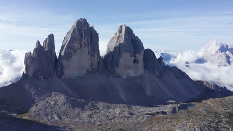 Aerial-flight-towards-famous-Tre-Cime-Di-Lavaredo-towers-during-sunrise-with-dense-cloudscape-in-background