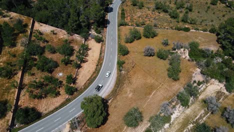 Aerial:-following-driving-cars-driving-on-the-Ibiza-road-in-Ibiza,-Spain