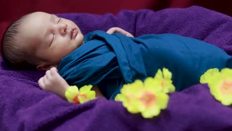 cute-newborn-baby-sleeping-in-baby-wrap-with-flowers-in-unique-style-from-top-angle-shot