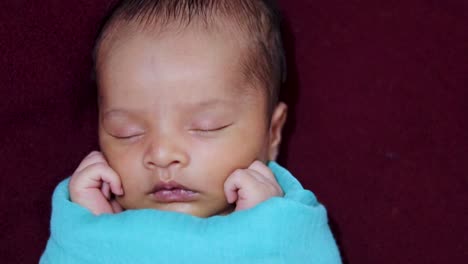 cute-newborn-baby-sleeping-in-baby-wrap-top-angle-shot