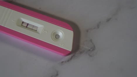 Gleitaufnahme-Eines-Positiven-Rosa-Schwangerschaftstests-Auf-Der-Marmortischplatte