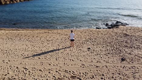 Man-standing-at-lonely-beach-in-corsica