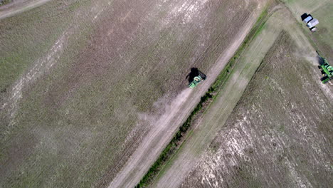 Drone-footage-of-soy-bean-harvesting-on-a-farm-field-with-a-harvester-or-tractor,-rotating-downward-angle-aerial-shot