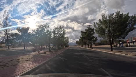 Driving-through-a-Mojave-Desert-town---driver-point-of-view-with-cloudscape-hyper-lapse