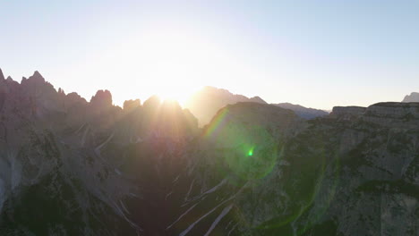 Glowing-sunrays-across-Tre-Cime-rocky-mountain-ridges-aerial-view-over-South-Tyrol-radiant-sunrise-landscape